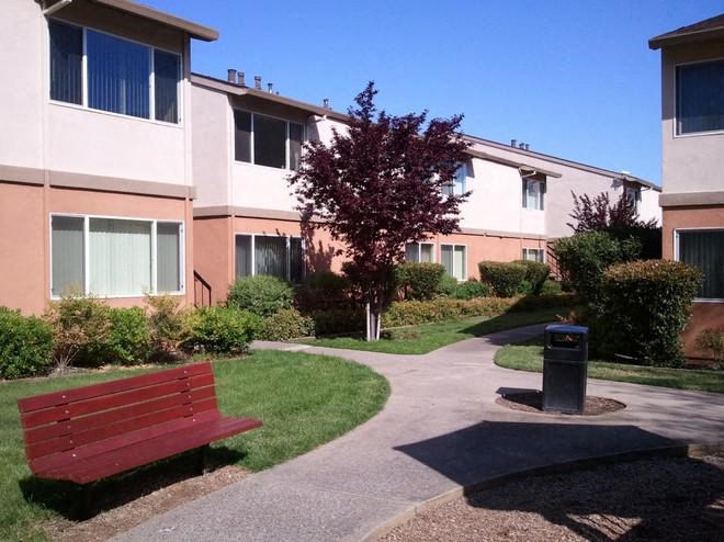 a red bench sitting in front of an apartment building