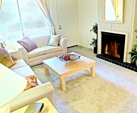a living room with couches and a table in front of a fireplace
