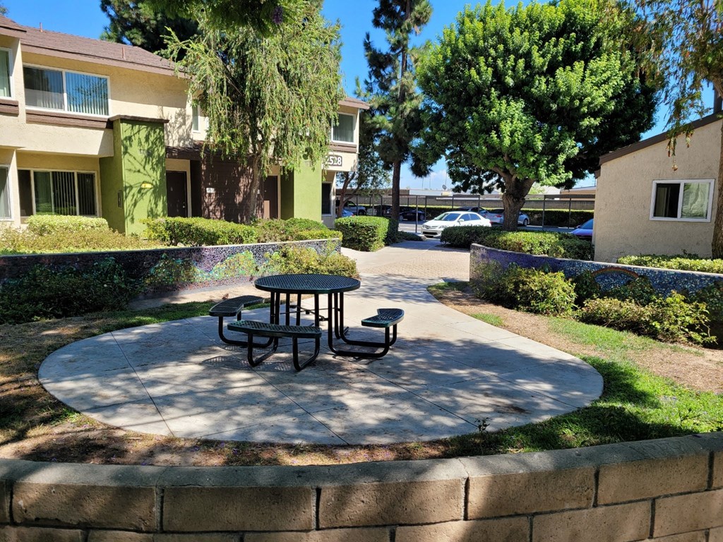 a patio with a table and benches in front of a building