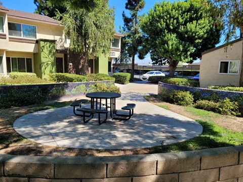 a patio with a table and benches in front of a building