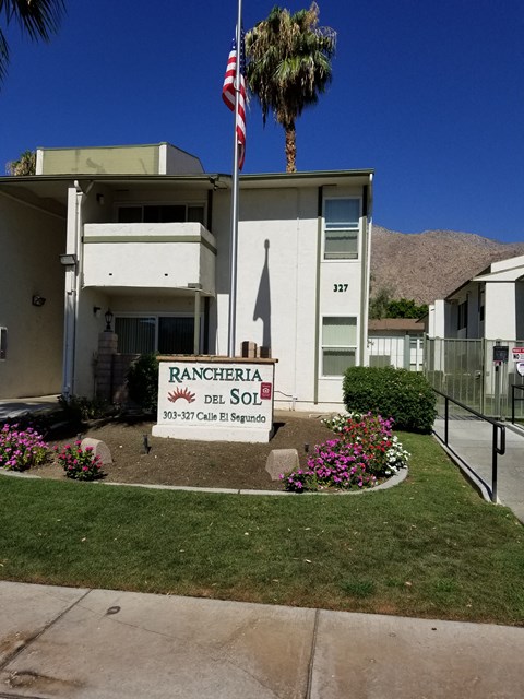a building with a sign and a palm tree in front of it