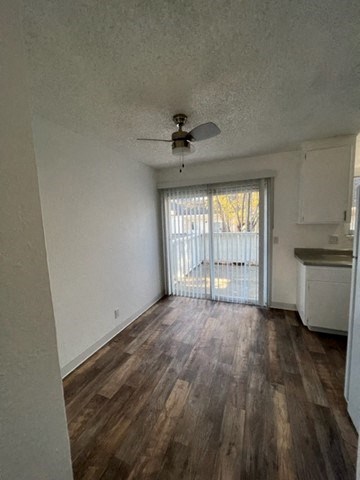 a living room with a ceiling fan and a door to a balcony