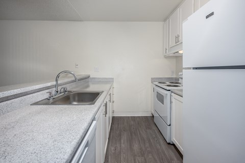 A kitchen with a white fridge, sink and stove.
