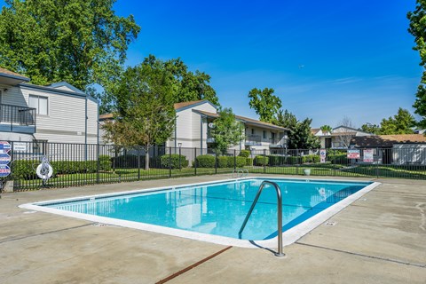 A swimming pool in a residential area surrounded by houses and trees.