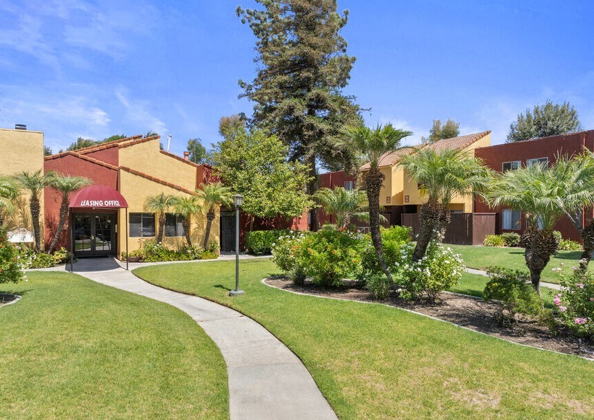 a sidewalk in front of a building with palm trees at Brookhollow Apartments, California