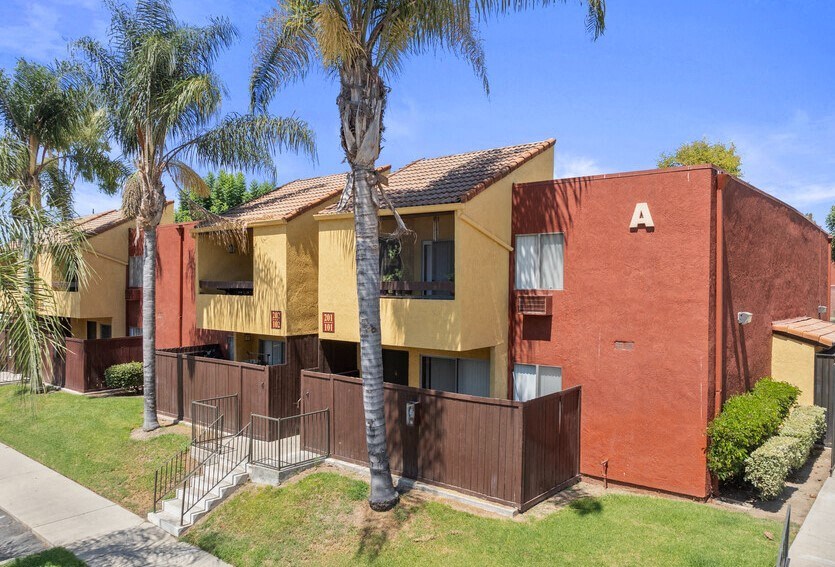 a yellow and red apartment building with palm treesat Brookhollow Apartments, West Covina , CA