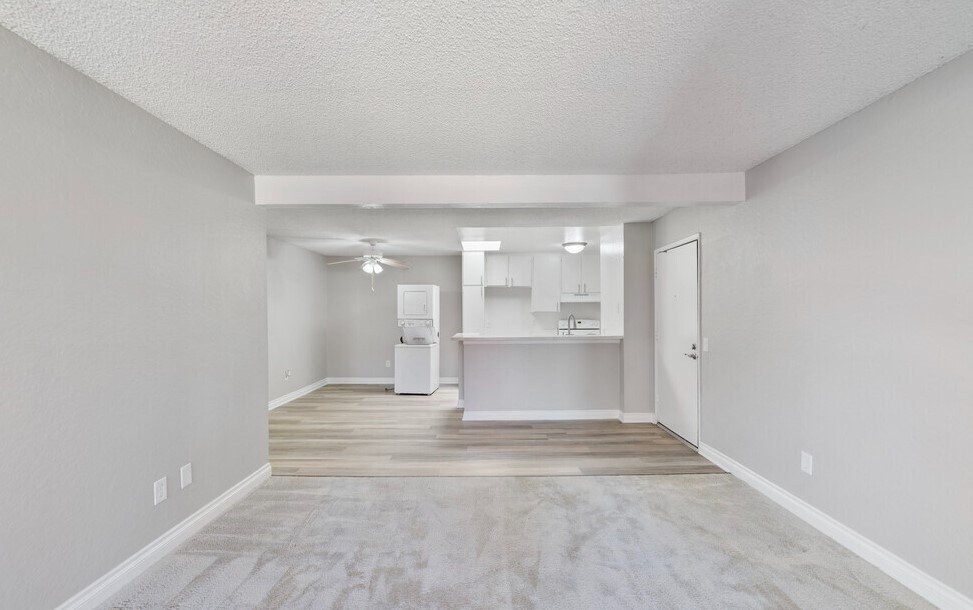 an empty living room with a kitchen in the background at Brookhollow Apartments, West Covina , CA