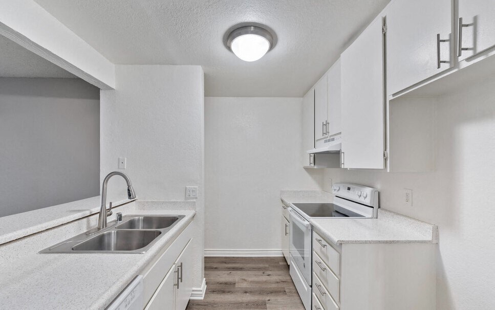 an empty kitchen with white cabinets and a sink at Brookhollow Apartments, West Covina , CA