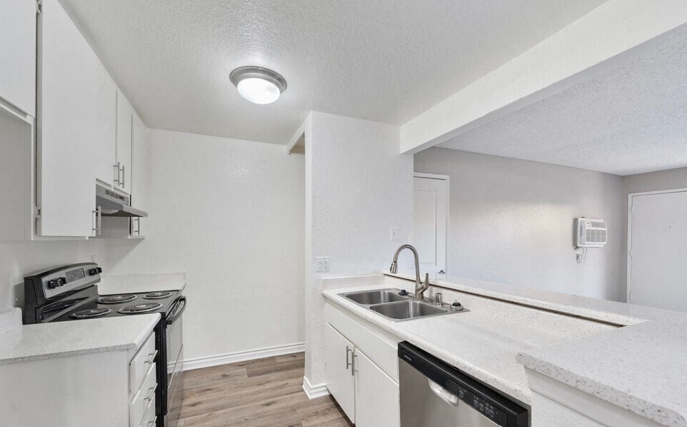 an empty kitchen with white cabinets and a stove and sink at Brookhollow Apartments, West Covina ,California, 91792