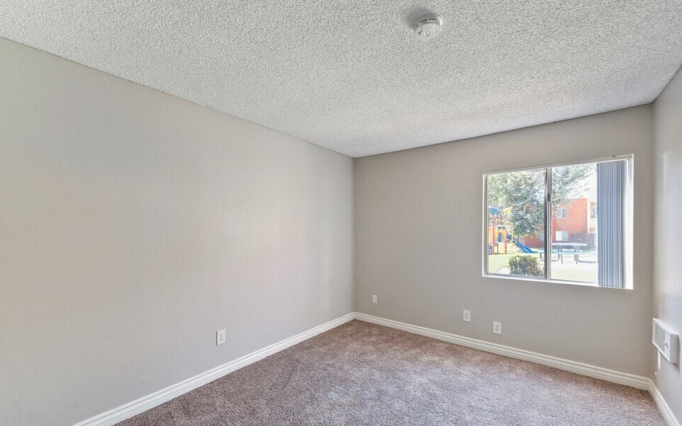 an empty room with carpet and a window at Brookhollow Apartments, West Covina 