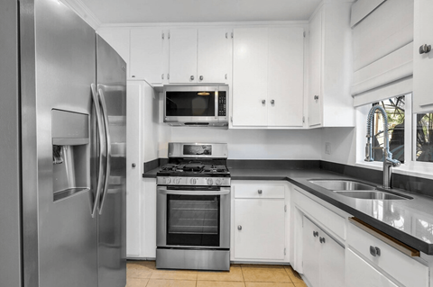 A modern kitchen with white cabinets and stainless steel appliances.