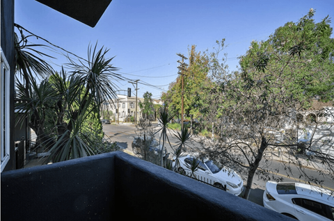 A view from a balcony overlooking a parking lot and trees.
