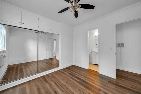 A room with a ceiling fan and wooden floors.