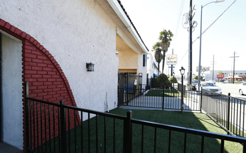A white house with a red arched doorway and a black fence.