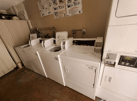 A row of white washing machines in a laundry room.