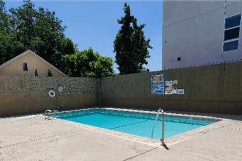 A small pool with a diving board in the middle of a concrete floor.