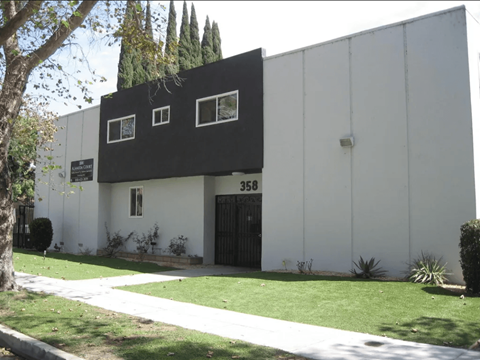 A white building with black trim and windows is numbered 358.
