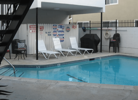 A pool with a black umbrella and white chairs.