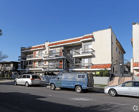 A blue van is parked in front of a multi-story building.