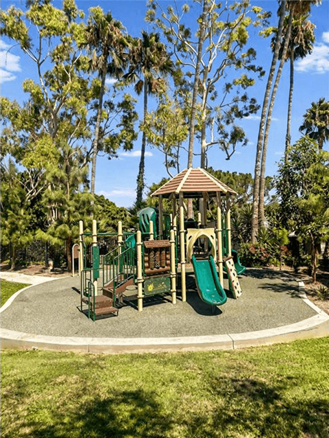 A playground with a green slide and a brown roofed structure.