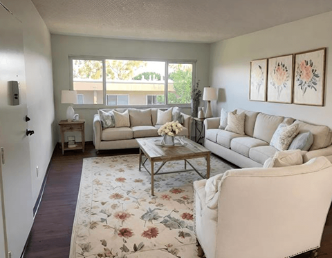 A living room with a white couch, a coffee table, and a rug with a floral pattern.