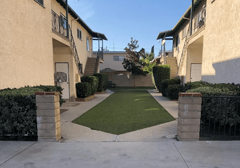 A courtyard surrounded by buildings with a green lawn in the middle.