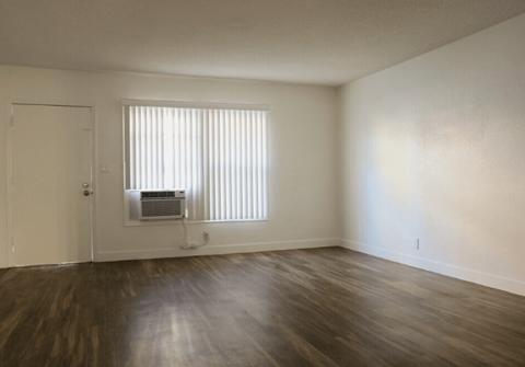 A room with wooden floors and a window with blinds.