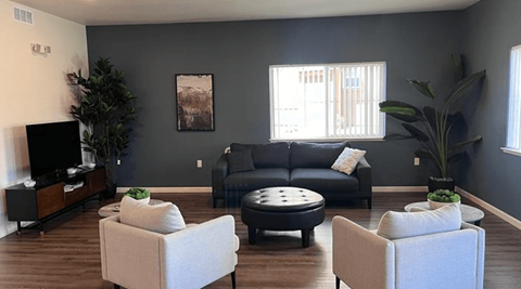 A living room with a black couch, a white chair, and a coffee table.