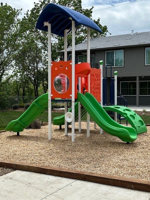 A playground with a green slide and a red and white structure.