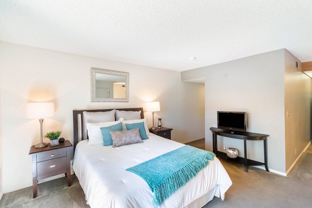 A bedroom with a large bed and a television at Chaparral Apartments, Palmdale, CA