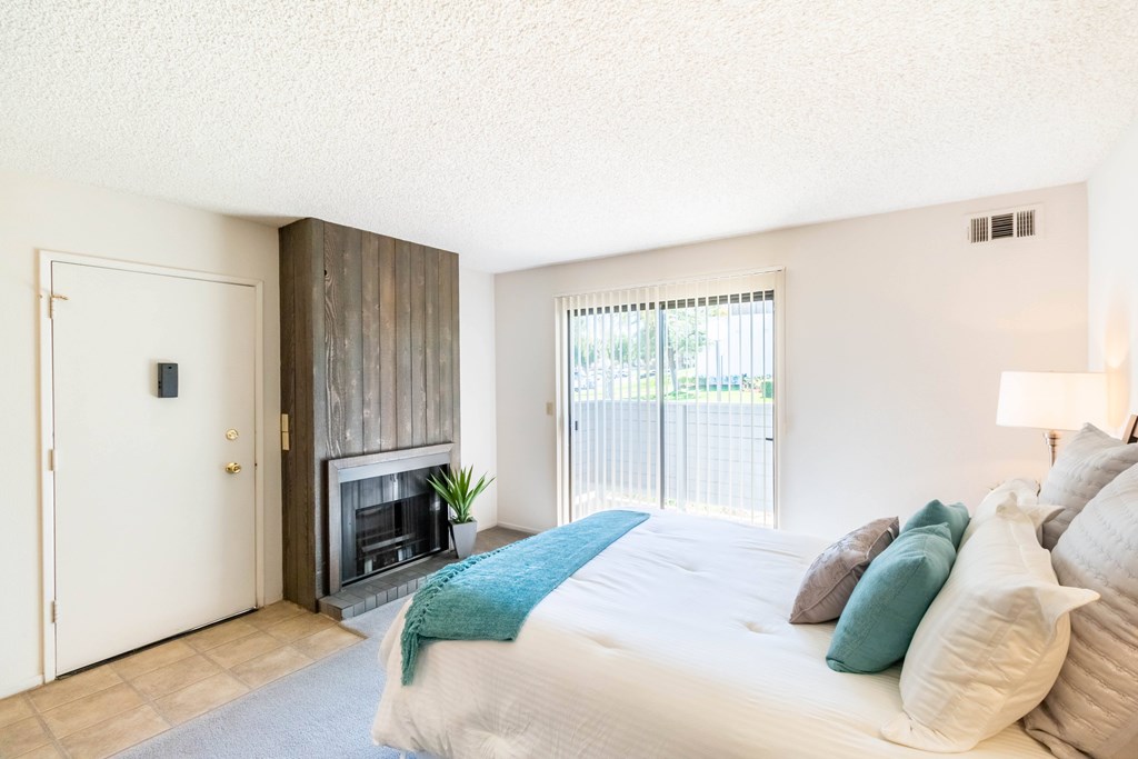 A bedroom with a large bed and a fireplace. at Chaparral Apartments, California, 93551