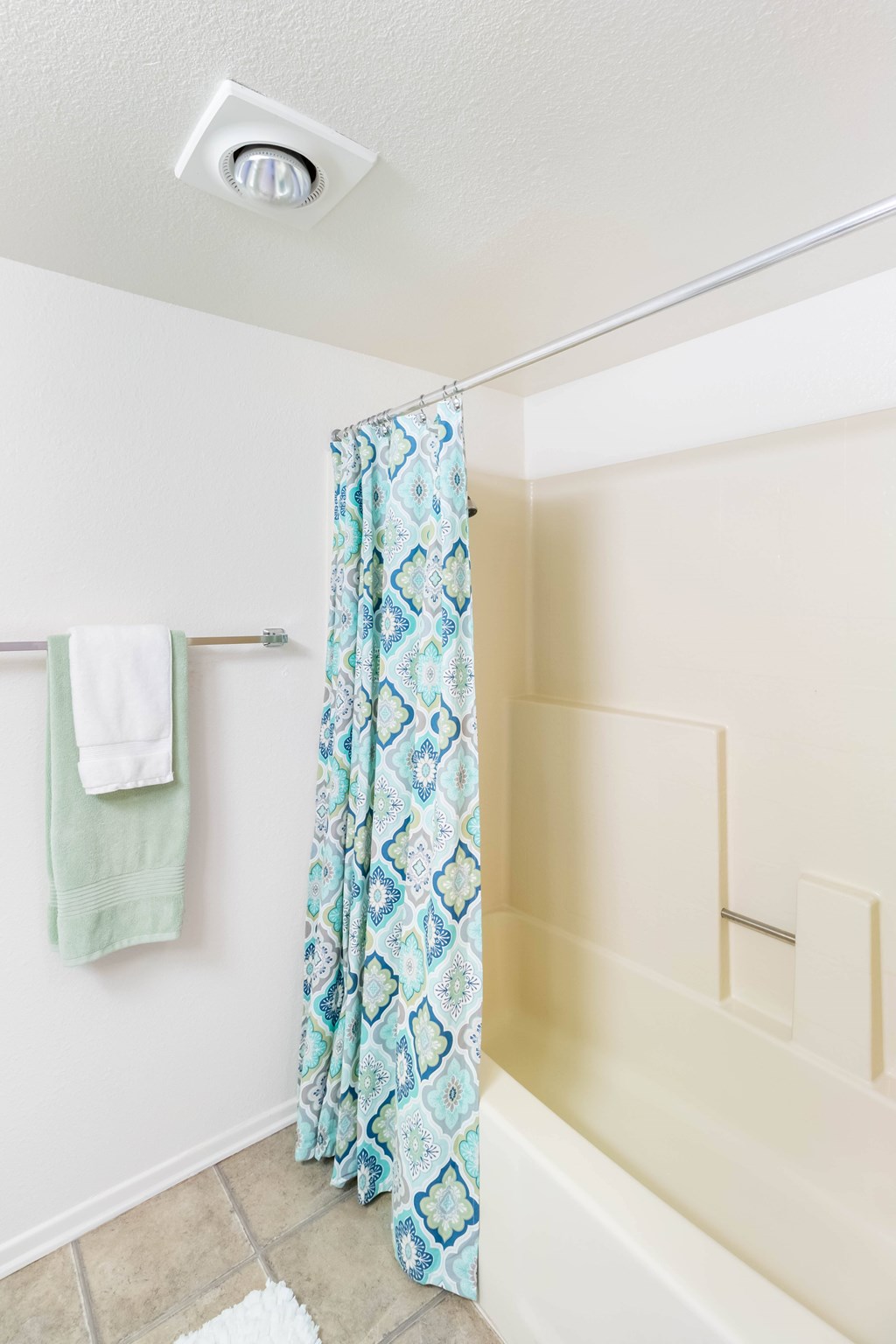 A bathroom with a shower curtain and a towel hanging on the wall at Chaparral Apartments, California, 93551