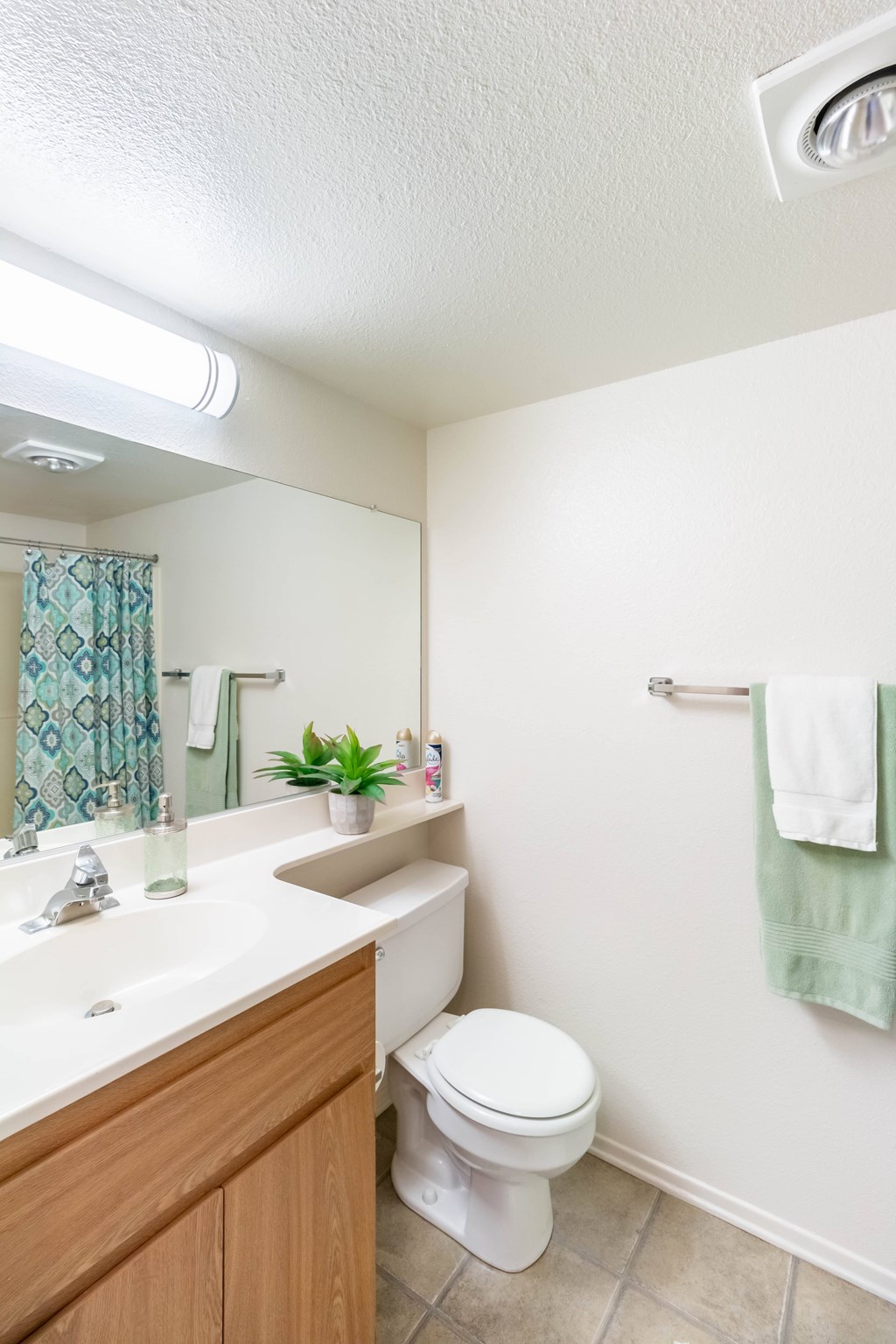 A white toilet sits in a bathroom next to a sink at Chaparral Apartments, California