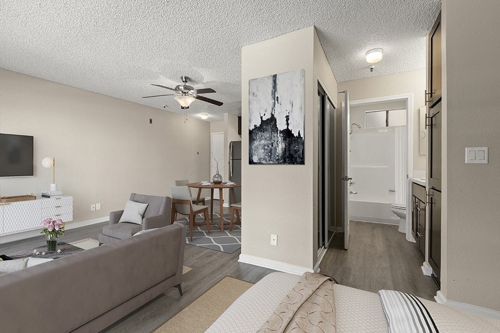 A living room with a grey couch and a painting on the wall in a studio apartment at Harbor Terrace Apartments, California, 90731