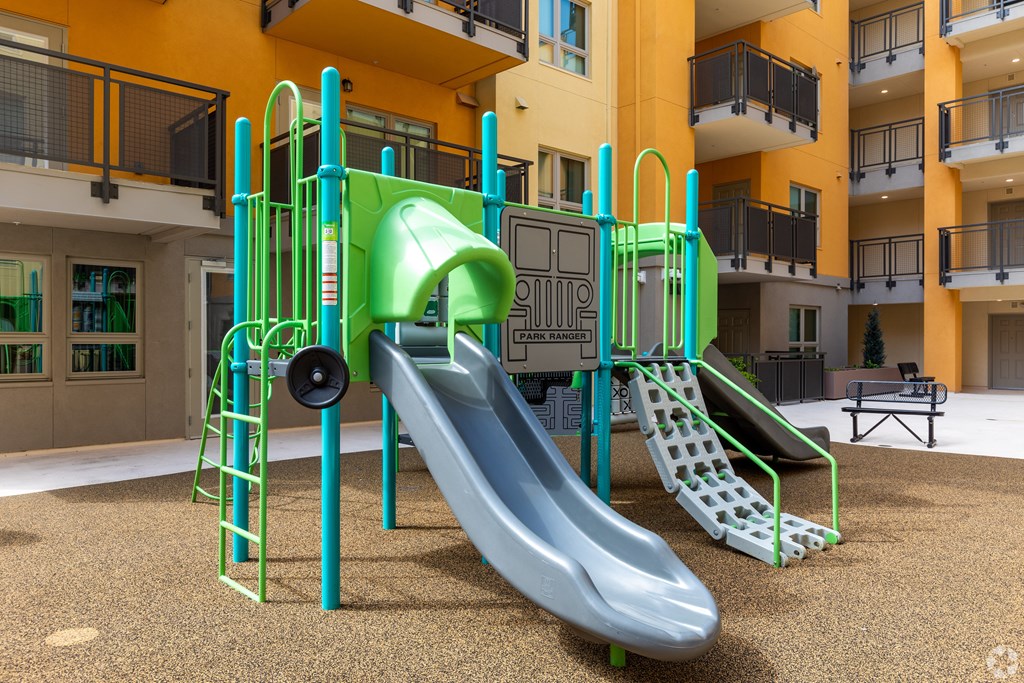 A playground with a green slide and a grey slide.