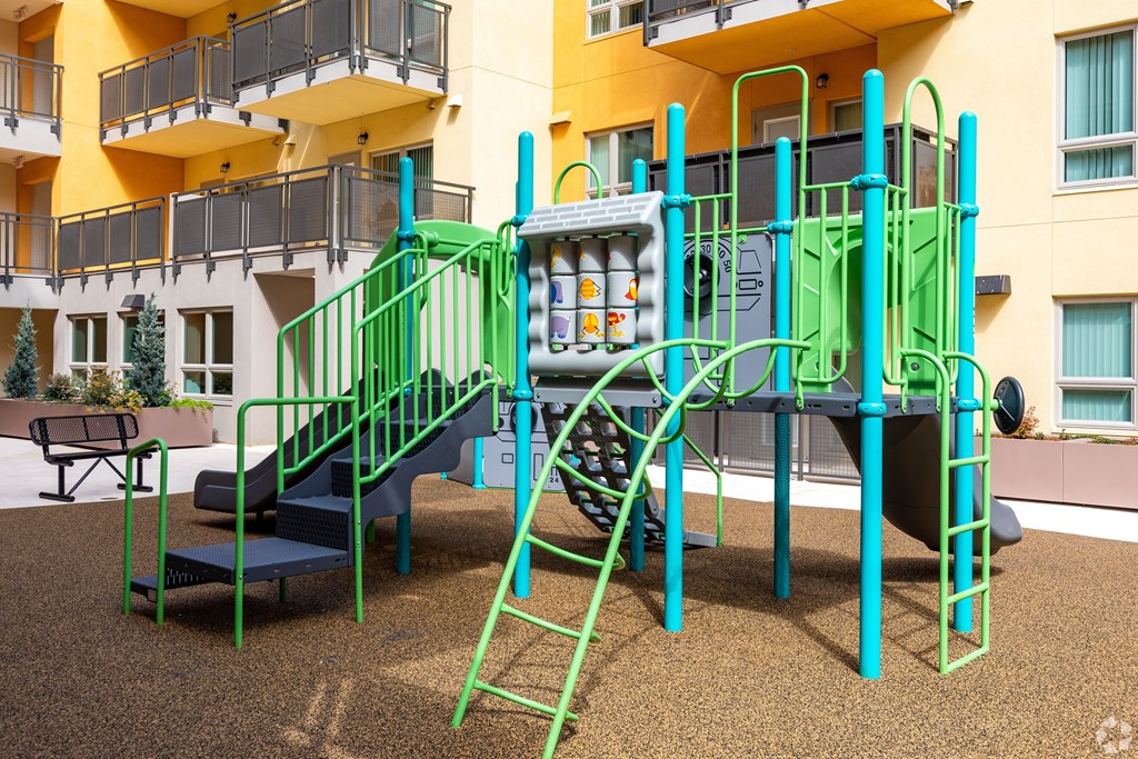 A playground with a green slide and a blue bench.