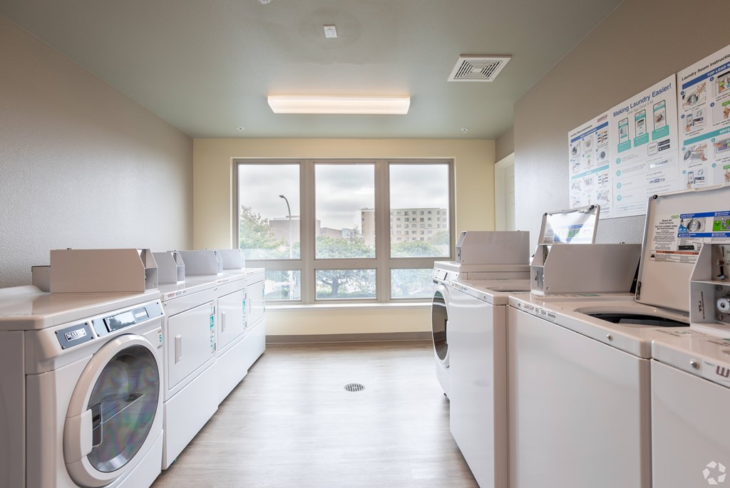 A laundromat with rows of washing machines and a window in the background.