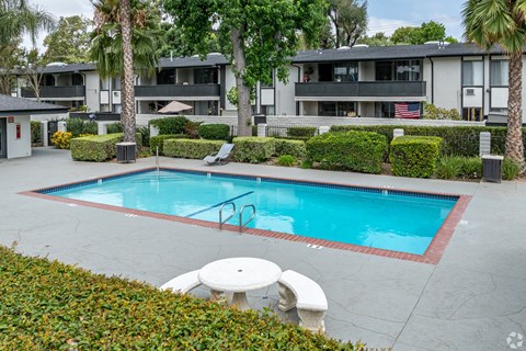 A swimming pool surrounded by a white table and chairs.