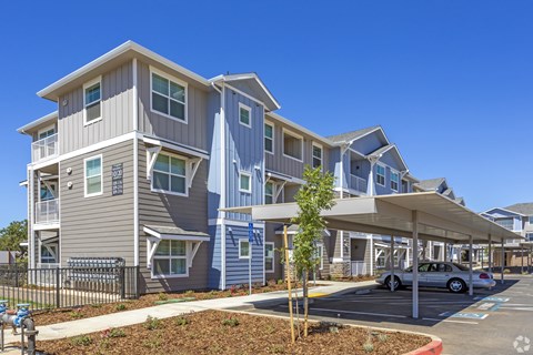 A modern apartment complex with a parking area in front.