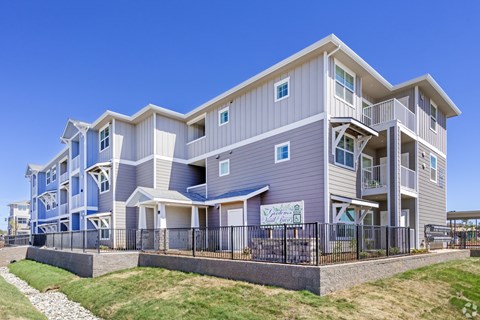 A modern two-story apartment building with a balcony on the second floor.