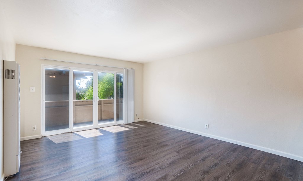 an empty living room with a sliding glass door to a patio