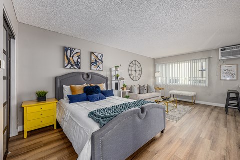 A bedroom with a bed, nightstand, and a yellow dresser at The Marquee Apartments, North Hollywood 91605