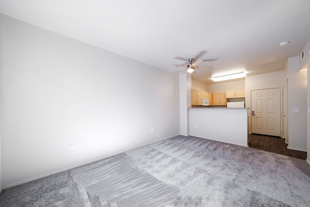 an empty living room with white walls and a ceiling fan