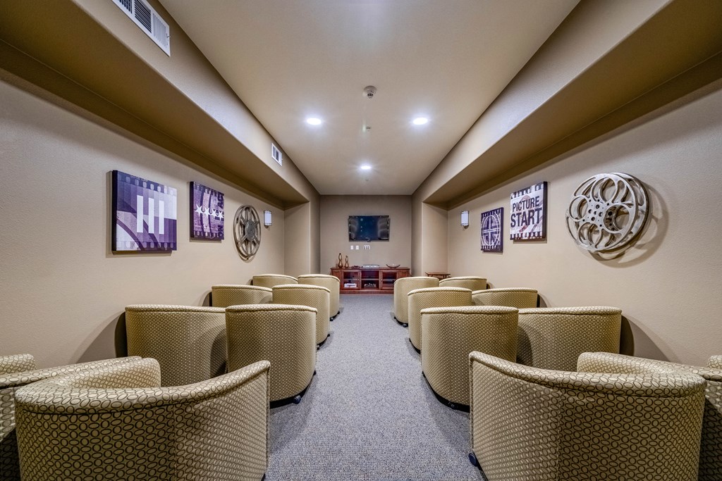 a movie room with large television filled with couch seating