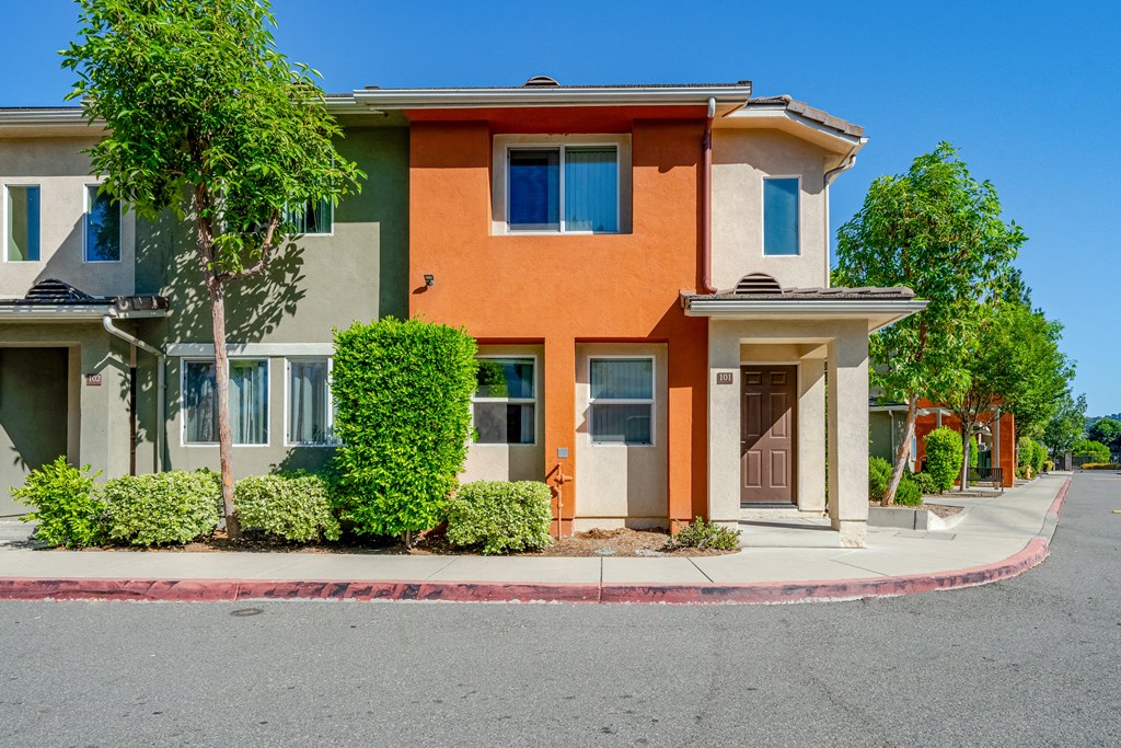 an orange and green house with a street in front of it