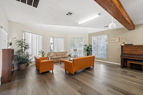 A living room with a couch, two chairs, and a piano.