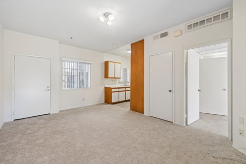A spacious room with a carpeted floor and white walls.