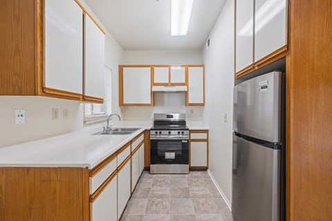 A kitchen with a stainless steel refrigerator and wooden cabinets.