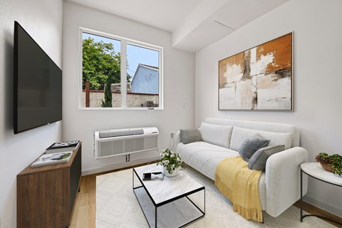 A living room with a grey couch, a coffee table, a flat screen TV, and a painting on the wall.
