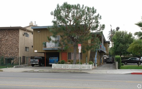 A building with a brown and tan exterior and a white picket fence in front.